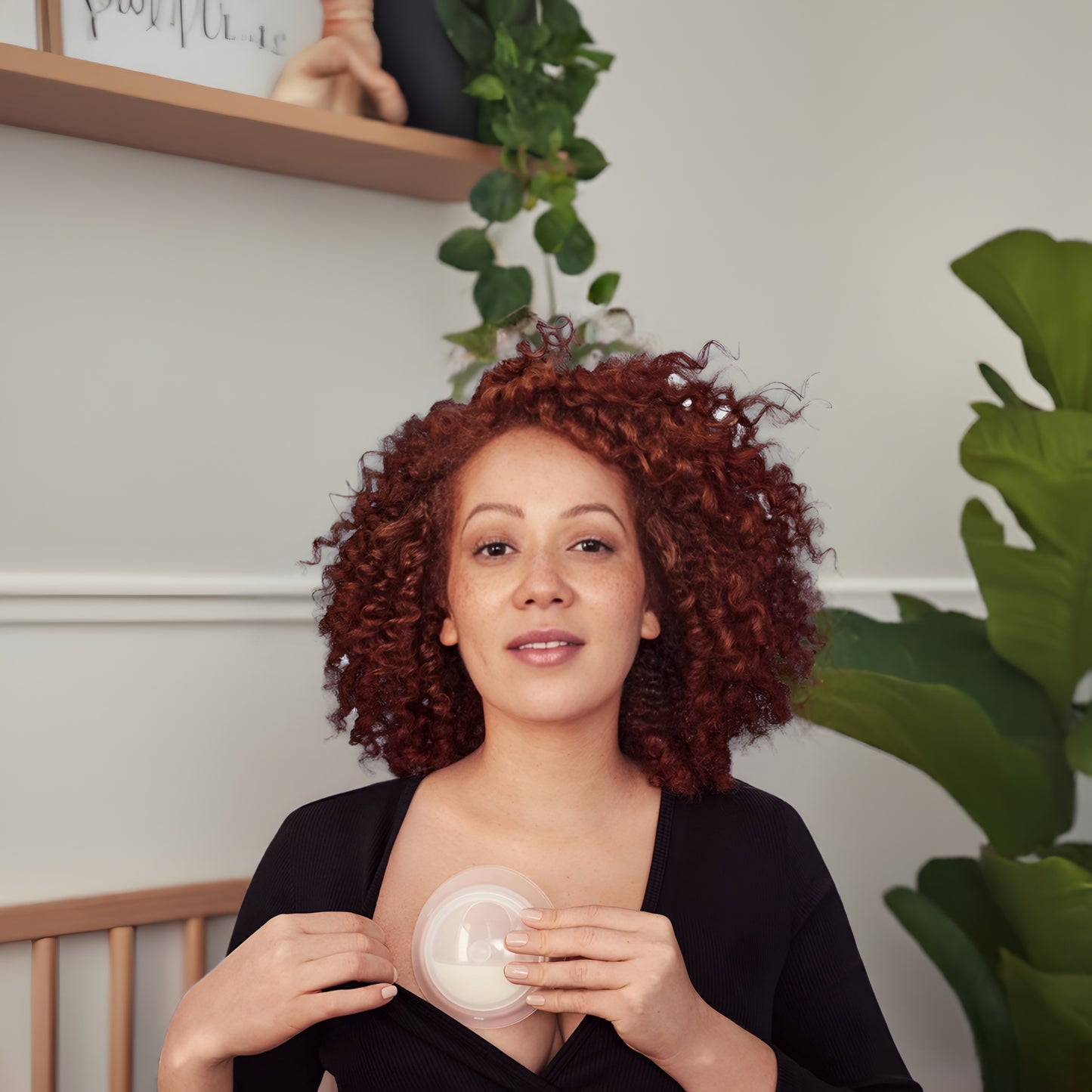 Woman using Elvie Catch milk collection cups for secure breastmilk saving.